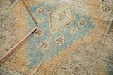 Distressed Oushak rug texture showing faded sky blue, sand, and brown geometric motifs.