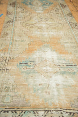 Distressed Oushak runner with short pile and visible foundation, featuring faded beige, blue, orange.