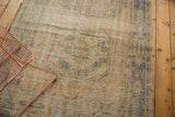 Distressed vintage Oushak rug surface showing mostly even wear, faded ivory, blue, and green.