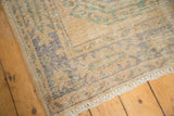Distressed Oushak runner corner, wear across knot heads, faded denim blue and celadon green geometric patterns.