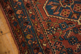 Hand knotted Engelas rug with brick red field, intricate Herati motif, and blue patterned border.