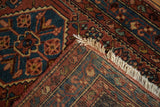 Vintage Engelas rug with brick red and blue Herati motif, showing woven end and white fringe.