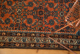 Vintage Hamadan rug's brick red Herati field meets ornate floral vine borders.
