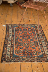 Hand knotted Hamadan rug corner with brick red field, patterned borders, and tinted fringe.