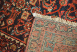 Vintage Malayer rug: worn madder red and navy pile, ivory fringe, hand-knotted back foundation.