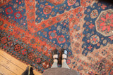 Textured antique Caucasian Soumac carpet section with geometric florals in madder red and indigo.