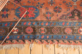 Blush red and indigo geometric patterns with tattered fringe detail on an antique Soumac rug edge.