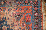 Antique Soumac carpet detail: geometric floral patterns, blush red, indigo, with wear and tattered edge.