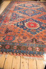 Tattered fringe and worn borders on an antique Soumac carpet with blush and indigo geometric designs.
