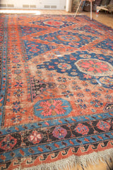 Tattered fringe and geometric borders of antique Caucasian Soumac carpet, with distressed red and blue patterns.