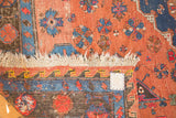 Close-up of the Soumac rug's tattered off-white fringe and geometric red, blue, and black border.