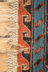 Blush red, blue, black geometric Soumac weave pattern with tattered cream fringe.