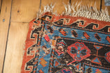Tattered corner of an antique Caucasian Soumac carpet, displaying worn geometric patterns and pile loss.