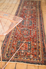 Geometric Heriz Karaja pattern in brick red, navy, and faded orange, with visible end fringe.