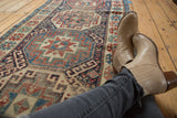 Antique Moghan Kazak runner displaying geometric motifs in deep gem tones.