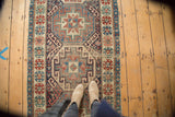 Saturated red, blue, and ivory geometric medallions on a Moghan Kazak style runner, with mostly even wear.