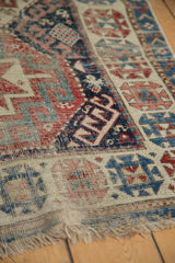 Antique Caucasian rug runner with geometric navy, red, and ivory border and reduced fringe.