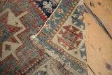 Hand-knotted antique Caucasian runner's geometric pattern in red, blue, ivory, with foundation visible.