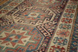 Geometric motifs and decorative border on an antique Caucasian runner, featuring navy, red, and ivory.