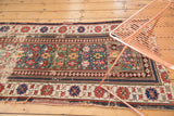 Antique Caucasian rug: geometric green field, wide patterned border, and visible wear.
