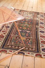 Geometric patterns and varied green field on an antique Caucasian rug with banded border.