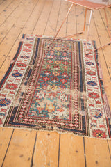 Geometric motifs, unusual green field, and visible wear on an antique Caucasian rug.