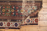 Worn corner of antique Caucasian rug, geometric patterns in teal, red, blue, and reverse side.