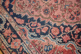 Pink and brick red floral vinery detail with navy border of a vintage Sarouk rug.