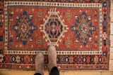 Vintage Karaja rug displaying classic triple medallion design, brick red field, and roundel floral border.