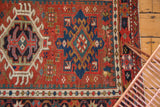 Detail of hand-knotted Vintage Karaja rug: geometric medallion, brick red field, colorful beaded, floral borders.