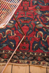 Vintage Lilihan rug close-up, featuring red arabesque patterns, indigo flowers, and tattered bottom edge.