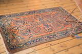 Corner of vintage Lilihan rug, showing dusty rose field, dark blue border, and scalloped floral spandrel.