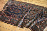 Folded vintage Hamadan rug, showing indigo Herati motif and blush, sky blue vine borders.