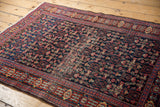 Vintage Senneh rug's navy Herati field, madder red trident border, and central wear.