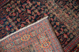 Vintage Senneh rug's folded corner, showing hand-knotted construction, dense pattern, and foundation wear.