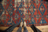 Antique Shirvan rug's geometric lattice in vivid red and blue with visible time-softened patina.