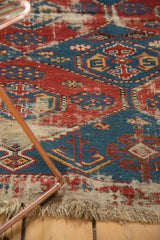 Antique Shirvan rug with worn red and blue geometric patterns and tattered fringe.