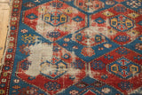 Close-up of worn red and blue geometric pattern with exposed foundation on antique Shirvan rug.