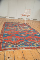 Frayed side detail of an antique Shirvan rug, with gem-tone red and blue geometric patterns.