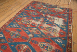 Antique Shirvan geometric rug showing cherry red, sky blue, gold patterns, and visible edge tatter.
