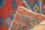 Antique Shirvan rug's hand-knotted pile with gem-tone geometric patterns and tattered fringe.