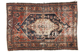 Antique Northwest Persian rug, oblong geometric medallion on red and navy field, showing heavy wear and patches.