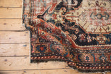 Worn texture, exposed foundation, and geometric red, navy designs on an Antique Persian rug.