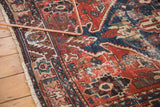 Visible hard wear and exposed foundation on an antique Persian rug's geometric red and navy pattern.