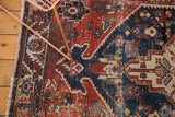 Antique Northwest Persian rug showing wear, visible foundation, and geometric patch in madder red, navy.