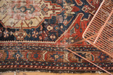 Antique Northwest Persian rug's geometric border in deep navy, madder red, showing visible wear.