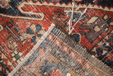 Antique Northwest Persian rug corner revealing geometric red, blue, beige pile, wear, and woven foundation.