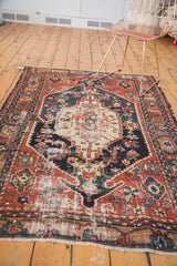 Antique Northwest Persian rug corner showing madder red border, navy geometric field, and wear.
