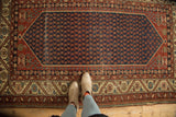 Antique Malayer rug with germinating seed boteh on navy field, serrated borders, floral spandrels.