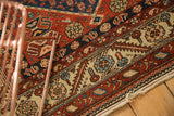 Antique Malayer rug, serrated border, boteh motifs, red, navy, ivory tones, visible wear, tattered edge.